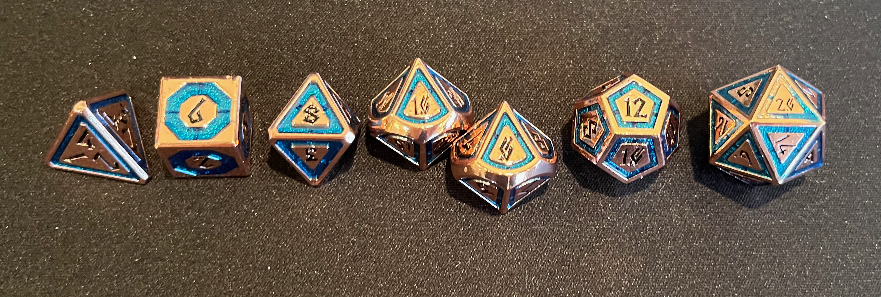 A set of 7 copper-and-blue metal dice seen from above. They have a Nordic/runic-inspired font face.