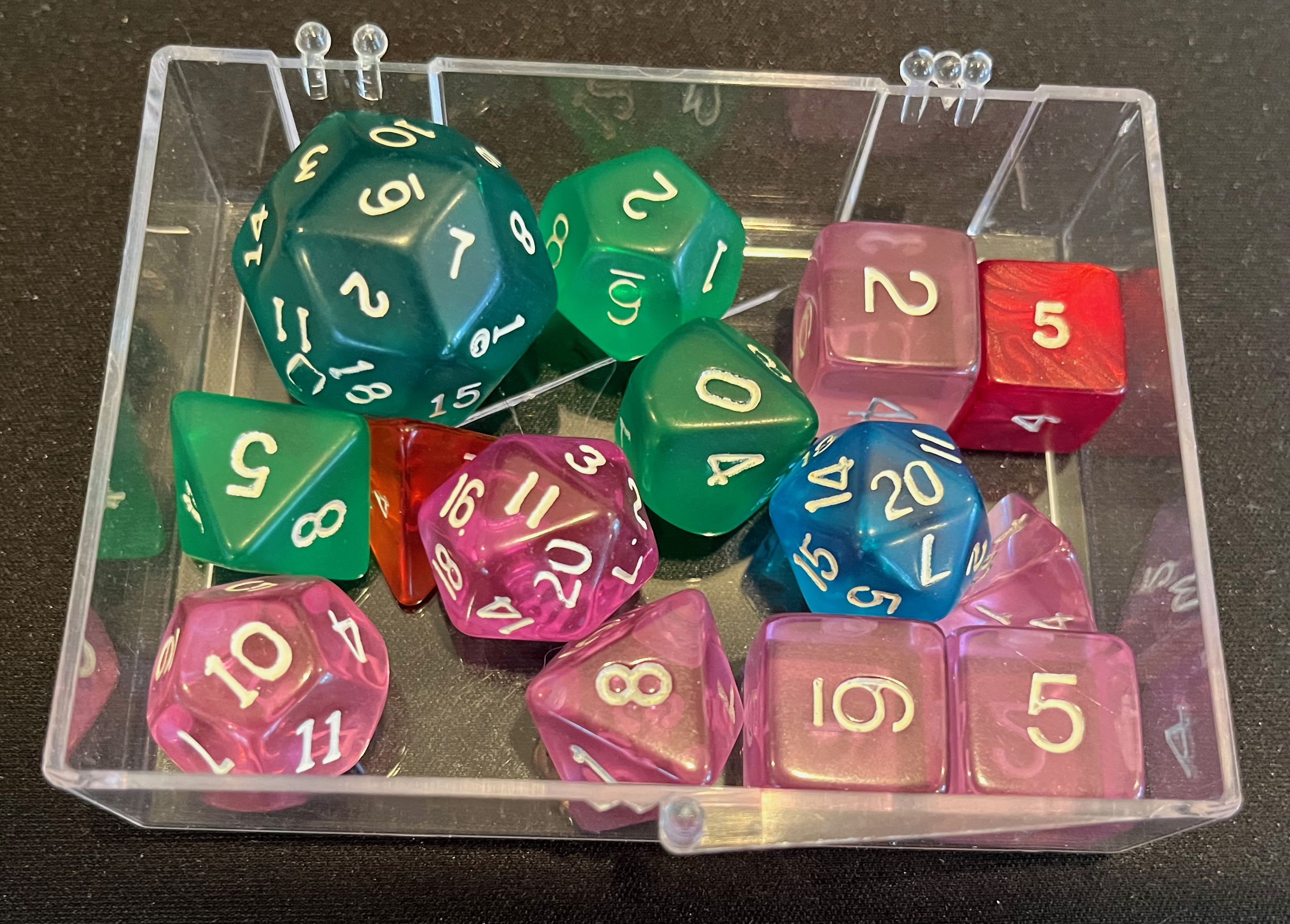 A motley collection of cheap translucent acrylic(?) dice in pink, with some greens, and the odd blue or red.